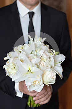 The groom holding a wedding bouquet of flowers in his hands, waiting for his bride. bridal bouquet of white lilies and