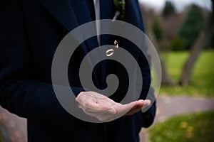 Groom holding wedding rings in hand. Two wedding rings on the floor with contrast wedding rings on floor, on ground, on piano, in