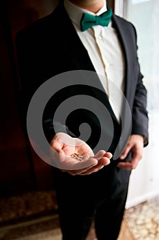 Groom holding wedding rings on the palm