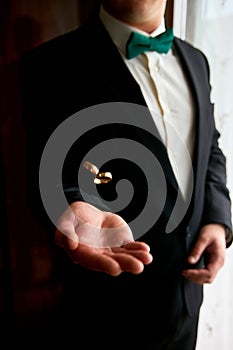 Groom holding wedding rings on the palm