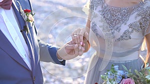 The groom holds the bride`s hand, the bride has a ring on her finger