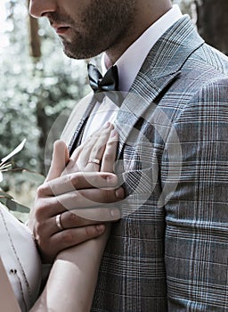 The groom holds the bride`s hand on his chest on the wedding day. oath. close up. selective focus.