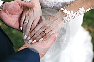 The groom holds the bride`s hands with a beautiful manicure and engagement ring with precious stone