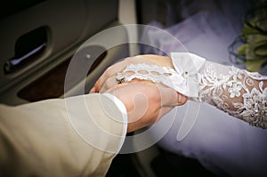 The groom holds the hand of the bride, who comes out of a limousine