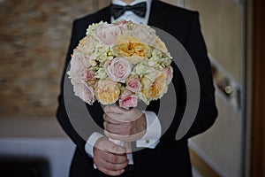 The groom holds in his hands a beautiful bouquet of the bride