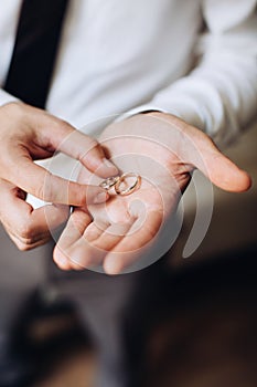 The groom holds in his hands golden wedding rings. Wedding accessories