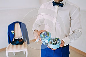 Groom holds a round box with Wedding rings with blue flowers. Artwork. Soft focus