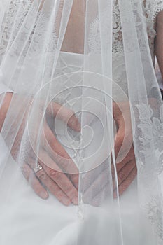 Groom hug bride by waist and his hands in heart shape symbol under bridal vail.