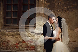 Groom huging kissing beautiful bride near wall outdoors Lviv