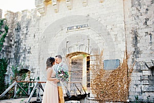 Groom hugs bride near the main entrance to Mamula Fort