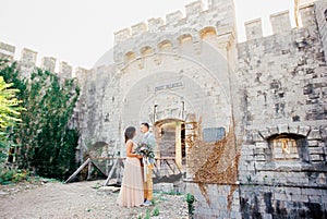 Groom hugs bride near the wooden bridge to the entrance to Mamula Fort