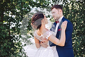 The groom hugs a young bride on the river bank