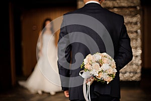 Groom keeping behind a bouquet of roses waiting for bride