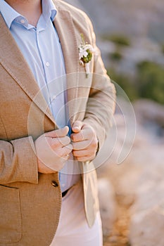 Groom keeps his hands on the lapels of his jacket. Close-up