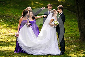 Groom kisses a bride while his friends grimaces behind him