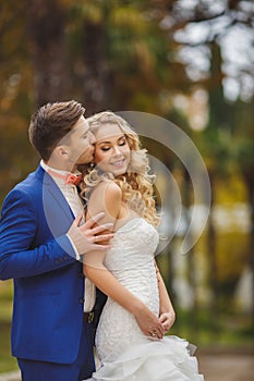 The groom kisses the bride in Park in the summer.