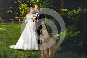 Groom kissing bride near fence in wood