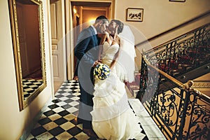 Groom is kissing bride shoulder on the background corridor with