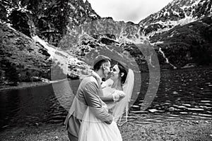 The groom kissing his young bride, on the shore of the lake Morskie Oko. Poland. Black and white photo