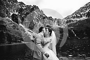 The groom kissing his young bride, on the shore of the lake Morskie Oko. Poland. Black and white photo