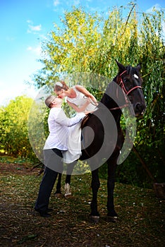 The groom leads the horse by the bridle. Bride sits in the saddl