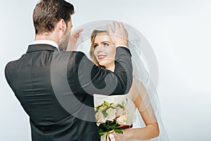 Groom looking at beautiful bride in veil with bouquet of flowers