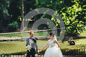 Groom looks at a bride walking with her along the lake shore