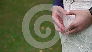 Groom making a heart sign while his arms are around his bride.