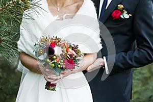 Groom with marsala boutonniere and bride with red rose bouquet