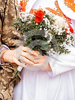 Groom in military uniform and bride with a bouquet