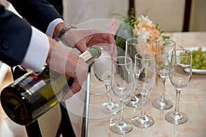 Groom opens a bottle of champagne before newlyweds.Bride and groom with friends drink champagne. Funny wedding moments