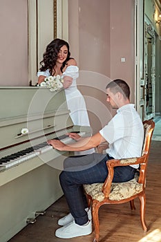 The groom plays on the piano. Grand piano wedding bride and groom music