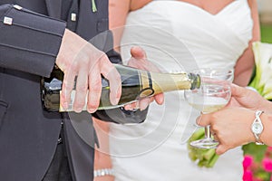 Groom pooring champagne on a glass