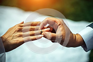 Groom put gold wedding ring on the bride`s finger, close-up. The wedding ceremony, exchange of rings