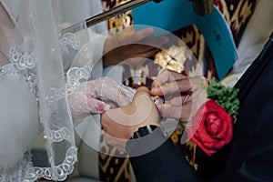 Groom put wedding ring on bride's finger.