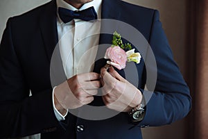 The groom puts on a boutonniere on a wedding day on a jacket