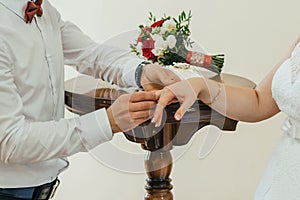 Groom puts a gold wedding ring on the bride`s finger