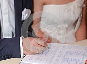 The groom puts her signature in the marriage document, selective focus