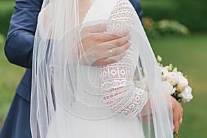 The groom puts his arm around the bride`s shoulders. Close-up of a hand with an engagement ring