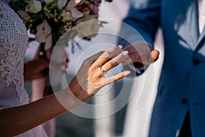 A groom puts the ring on the finger of bride