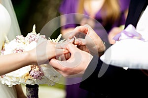 Groom puts a wedding ring on bride`s delicate finger