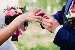 Groom puts a wedding ring on the bride`s finger