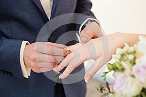 The groom puts the wedding ring on the bride`s finger.