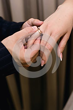 The groom puts wedding ring on the bride`s finger