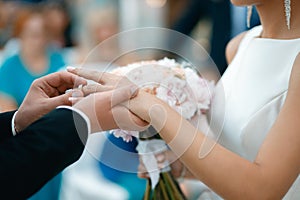 A groom puts a wedding ring on the bride`s finger