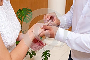 The groom puts the wedding ring on the bride`s finger at the wedding ceremony