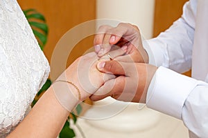 The groom puts the wedding ring on the bride`s finger at the wedding ceremony