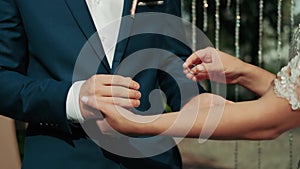 The groom puts the wedding ring on finger of the bride. The bride and groom exchange wedding rings.