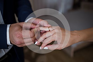 The groom puts the wedding ring on his finger