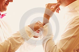 A groom putting on cuff-links